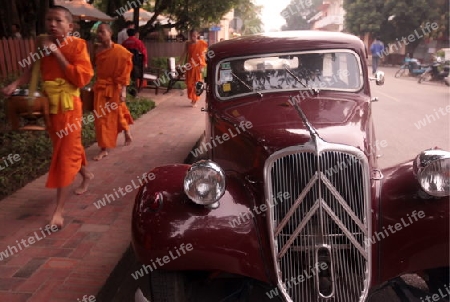 Moenche am fruehen Morgen beim einsammeln von Reis in der Altstadt von Luang Prabang in Zentrallaos von Laos in Suedostasien.