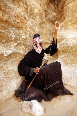 a Beduin women at work to spinning woll in the Temple city of Petra in Jordan in the middle east.