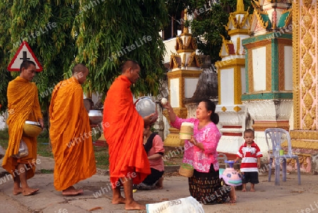 Moenche auf ihrem Rundgang am fruehem Morgen vor dem Tempel Wat Sainyaphum in der Stadt Savannahet in zentral Laos an der Grenze zu Thailand in Suedostasien.