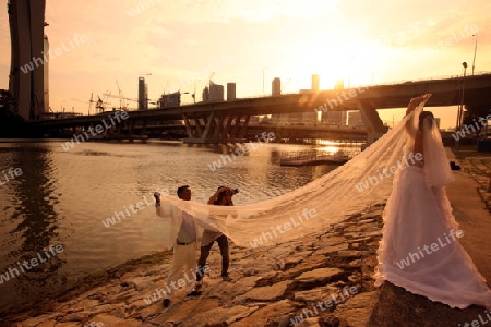 Ein Hochzeitspaar beim Fototermin beim Riesenrad mit der Skyline im Bankenviertel von Singapur im Inselstaat Singapur in Asien.