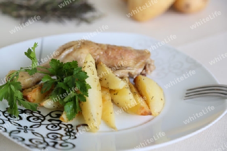 Gebackene kartoffeln mit huehnchen und frische petersilie auf dem weissen teller.