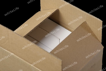 Halboffenes Paket mit weissen Schachteln als Inhalt und schwarzen Hintergrund.