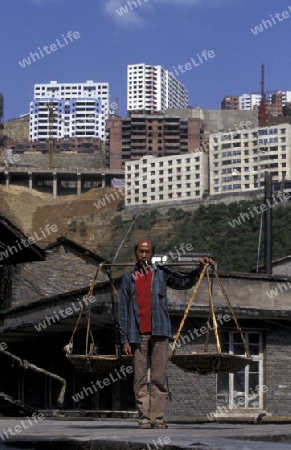 a men in the old city with the new city in the back in the city of wushan on the yangzee river near the three gorges valley up of the three gorges dam project in the province of hubei in china.