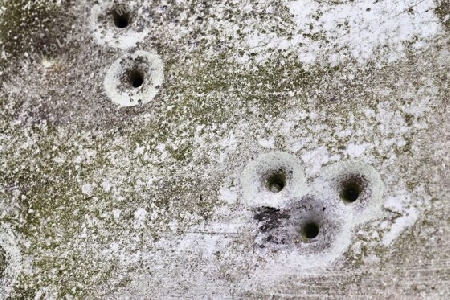 Detailed close up of bullet holes from gun shots in a german traffic sign