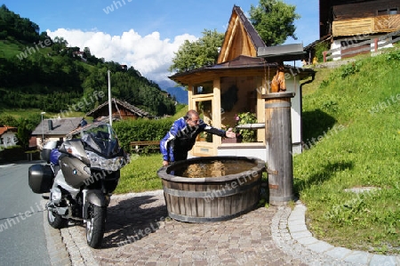 Motorradfahrer am Brunnen in Sellrain (nahe Innsbruck)