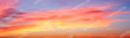 Beautiful high resolution panorama of orange and red sunset clouds in the evening sky.