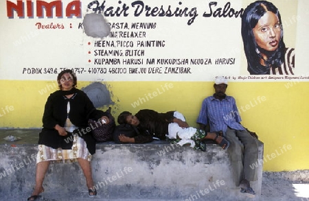 Eine Frau vor eimen Haarsalon bei Bwejuu an der Ostkueste der Insel Sansibar im Indischen Ozean in Tansania in Ostafrika..